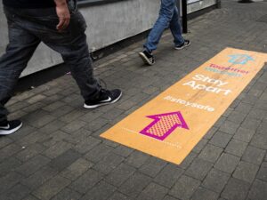 Photo of people walking next to covid sign