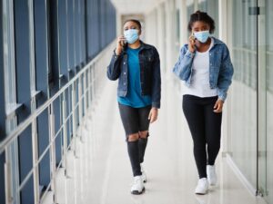 Photo of two women walking wearing masks