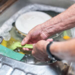 a man washing up in a sink. The photo focuses on his hands and forearms