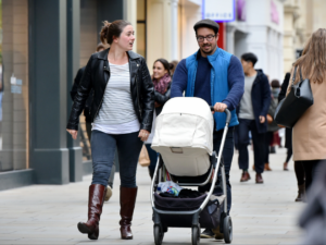 photo of couple walking with a baby in a pram