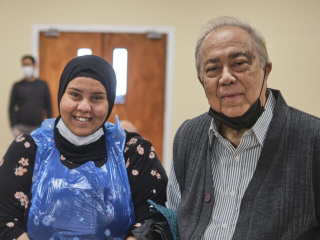A female carer in plastic gown and older male care recipient