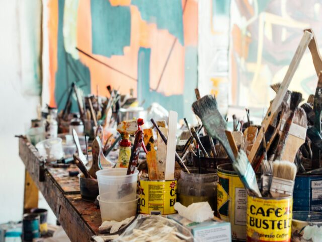 Photo of paintbrushes in pots on a workbench by Khara Woods on Unsplash