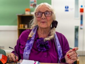 An older woman wearing purple smiles